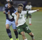 Vancouver Whitecaps forward Lucas Cavallini, left, and Portland Timbers defender Pablo Bonilla, right, battle for the ball during the first half of an MLS soccer match in Portland, Ore., Wednesday, Oct. 20, 2021. (AP Photo/Steve Dipaola)