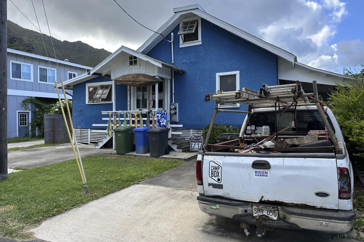 Blue house with white pickup truck in driveway with ladders on top and bumper stickers reading: Camp box and Biden Harris.