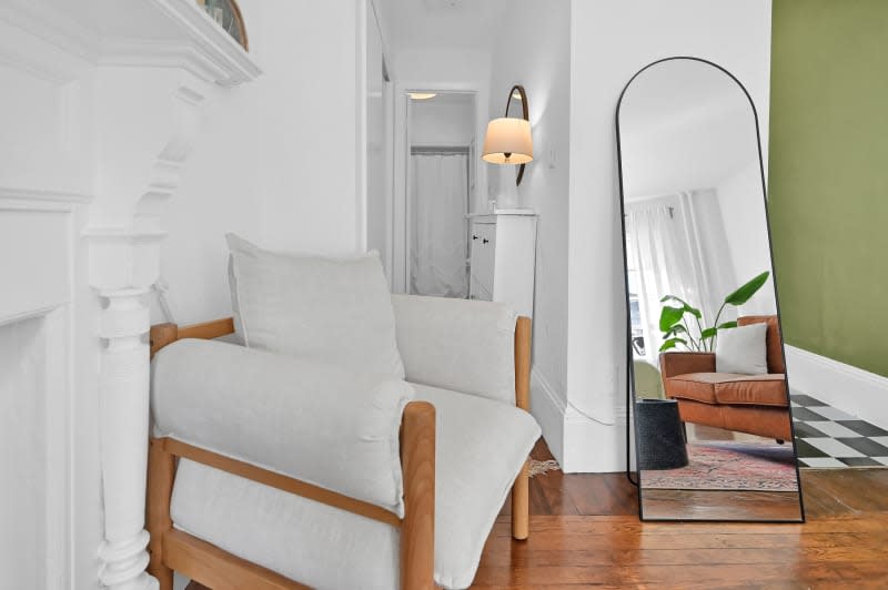 A lounge chair next to a large mirror  in a living room.