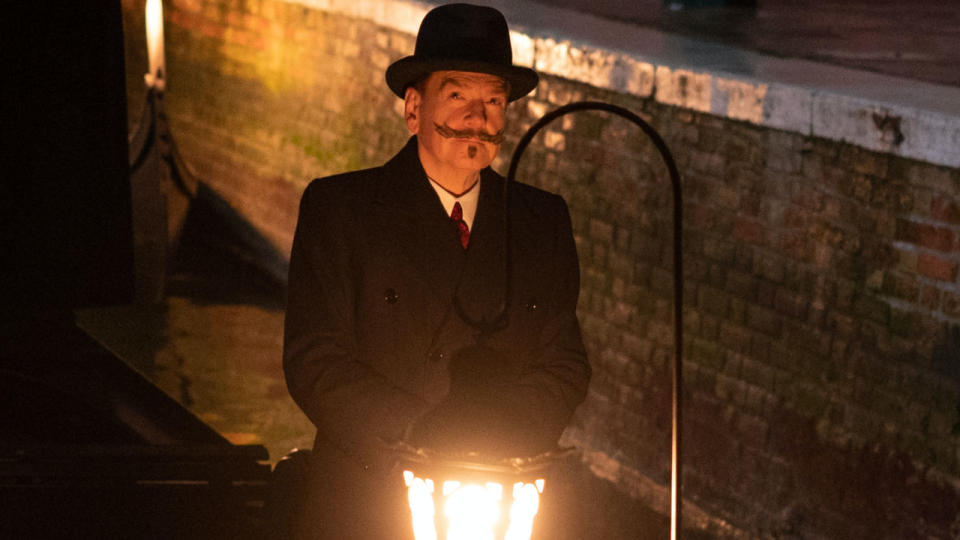 Kenneth Branagh stands on a gondola sailing at night in A Haunting in Venice.