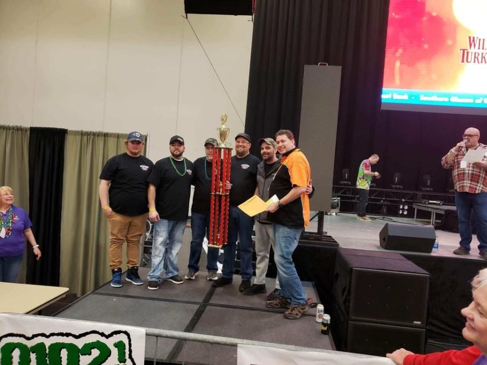 From left to right, Hyspeco employees Bailey, Nate Ervin, Dan Peacock, Chris Garrett and Taylor Dotson pose for a photo with their Grand Champion trophy and the awards announcer at the Sertoma Chili Cook-Off on Saturday, Feb. 18, 2023. 61 teams were a part of the competition.