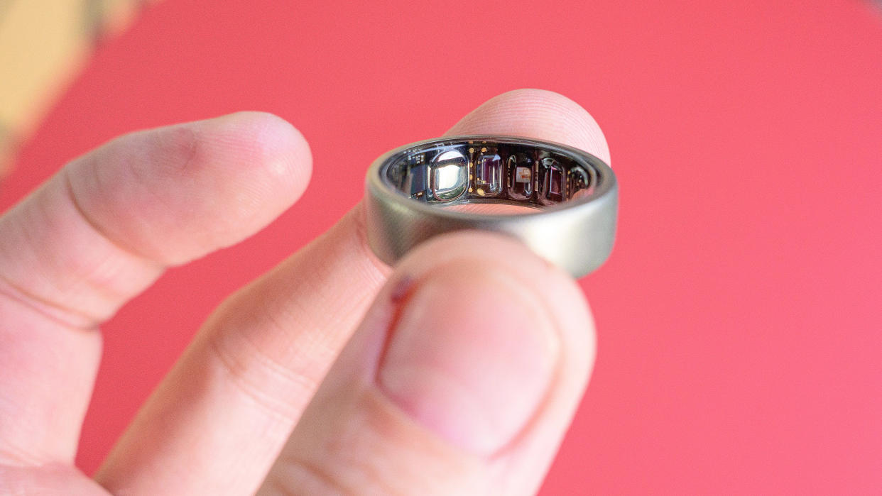  Amazfit Helio ring held in a user's finger's showing the sensors on the inside of the ring,. 