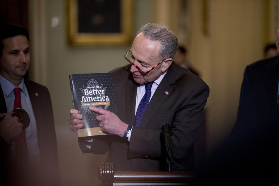 Senate Minority Leader Sen. Chuck Schumer of N.Y., center, accompanied by, Sen. Brian Schatz, D-Hawaii, left, holds up President Donald Trump's 2020 budget as he speaks following a Senate policy luncheon on Capitol Hill in Washington, Tuesday, March 12, 2019. (AP Photo/Andrew Harnik)