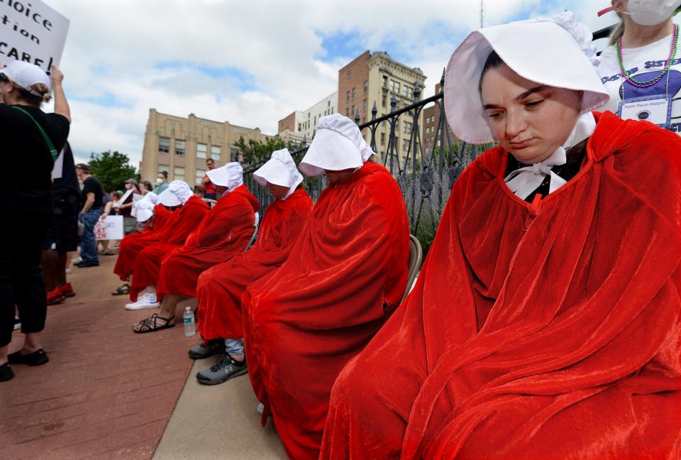 Mary Jewett of Springfield, right, dresses with others as a characters from Margaret Atwood's dystopian novel, "The Handmaid's Tale," during the Bans Off Our Bodies Roe Reaction Rally on Saturday in front of the Old State Capitol.