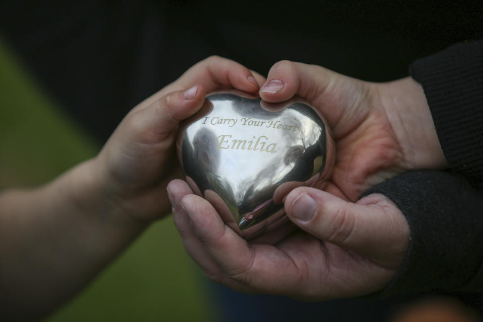 Jillian Philips and her sons, Jude and Emmett, hold an urn containing some of the ashes of her daughter, Emilia Phillips, Tuesday, May 2, 2023, in North Brookfield, Mass. The urn is housed in a teddy bear that daughter Macy sleeps with nightly. Philips, who used the drug Mifepristone to manage her miscarriage, is concerned that other women who miscarry could suffer if the pill, also used for abortions, is taken off the market. (AP Photo/Reba Saldanha)