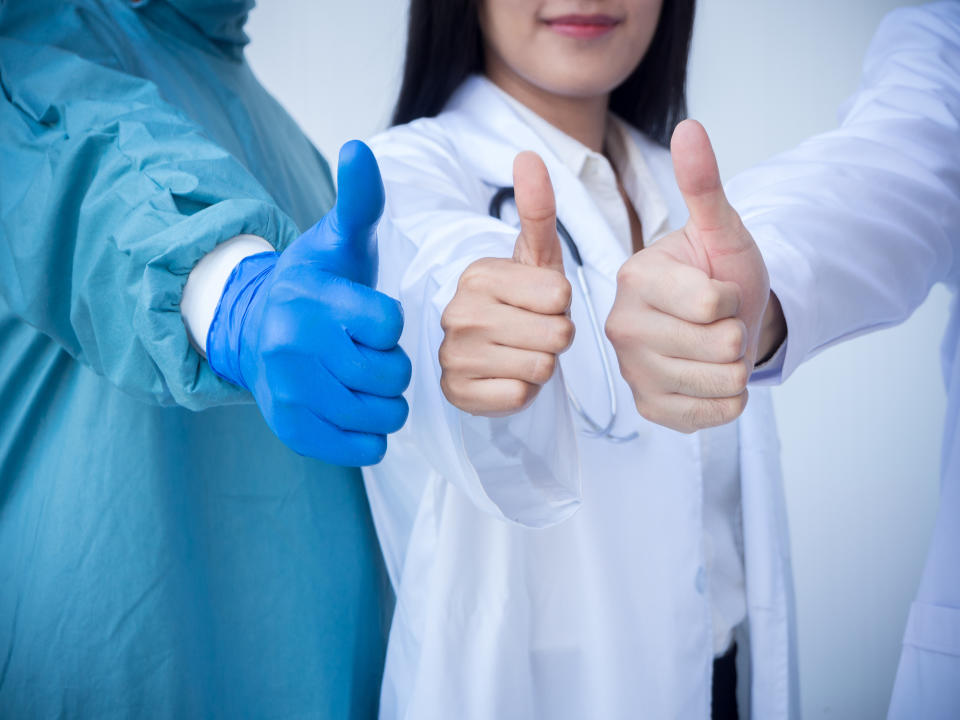 Three healthcare professionals with their thumbs up.