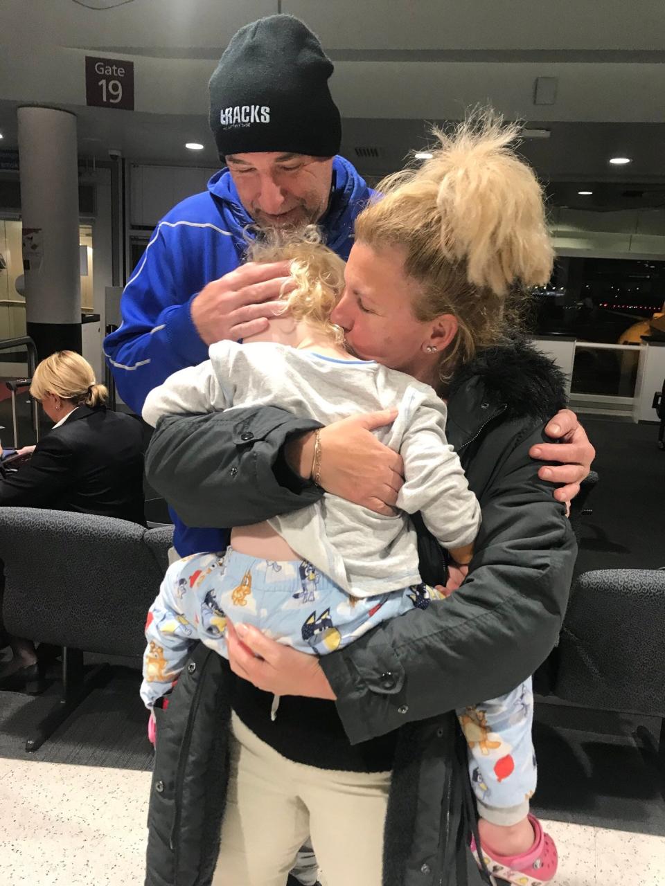 Then-3-year-old Poppy Wells gets a hug from her grandparents, Ian and Peggy McElligott, at the airport in July 2020.