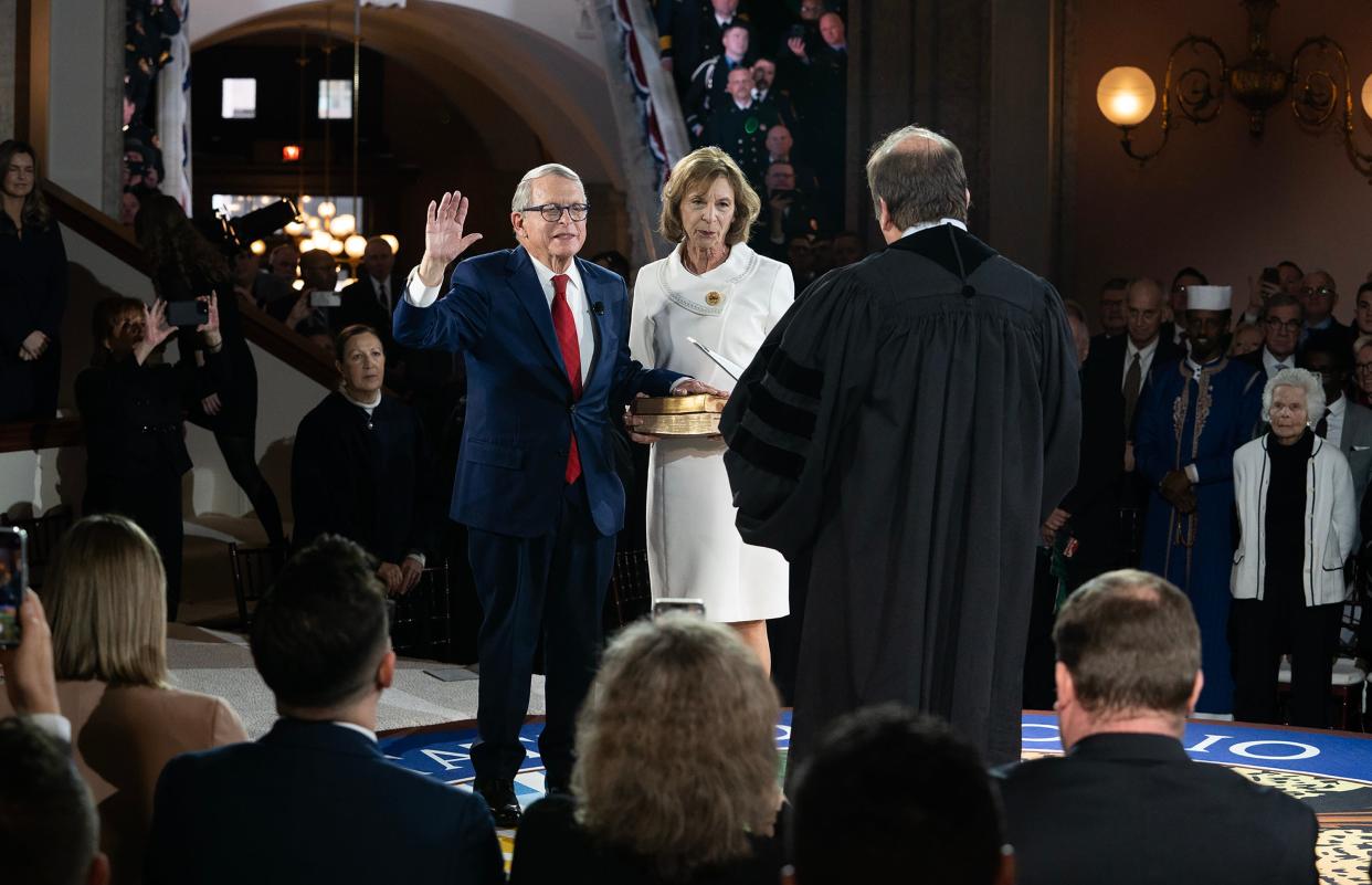 Ohio Governor Mike DeWine takes the oath of office accompanied by his wife Fran DeWine during inaugural ceremony at the Ohio Statehouse on Monday. Their son, Ohio Supreme Court Justice Pat DeWine swore in the governor.