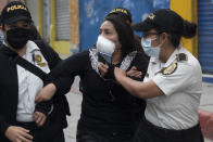 A woman is detained by police near the Congress building after protesters set a part of the building on fire, in Guatemala City, Saturday, Nov. 21, 2020. Hundreds of protesters were protesting in various parts of the country Saturday against Guatemalan President Alejandro Giammattei and members of Congress for the approval of the 2021 budget that reduced funds for education, health and the fight for human rights. (AP Photo/Moises Castillo)