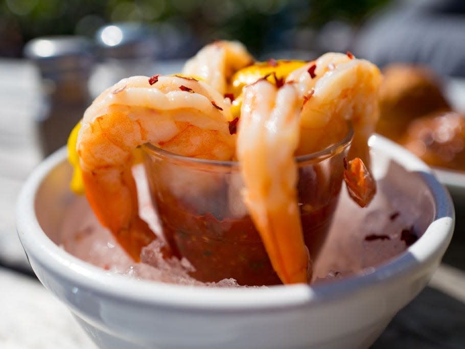 Shrimp cocktail in a white bowl with cocktail sauce and ice