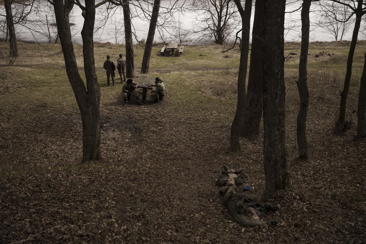 Ukrainian soldiers, top left, stand near the bodies of two Russian soldiers in Trostsyanets, Ukraine, Monday, March 28, 2022. Trostsyanets was recently retaken by Ukrainian forces after being held by Russians since the early days of the war. (AP Photo/Felipe Dana)