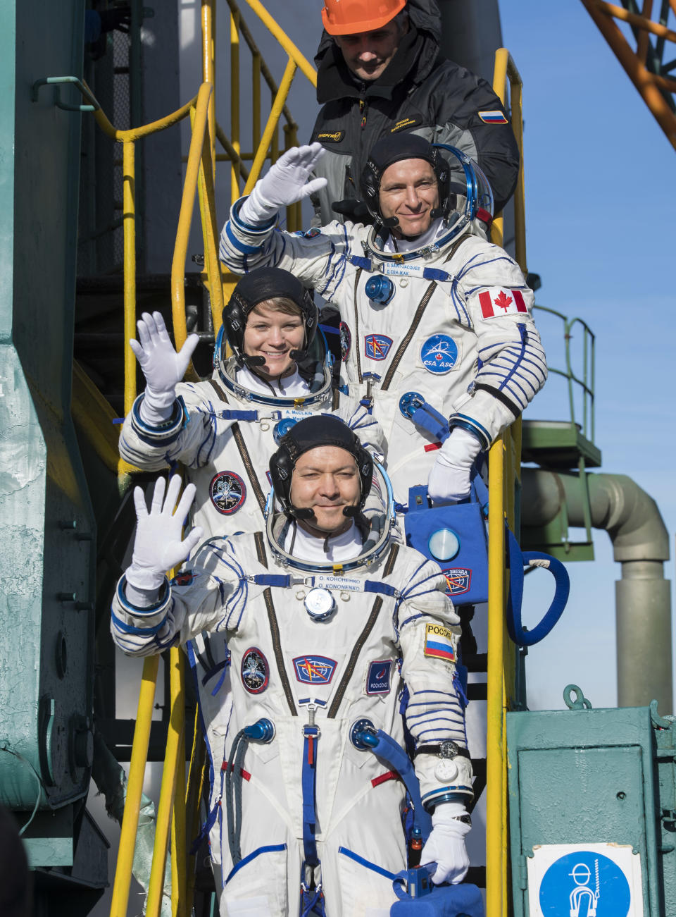 Expedition 58 Flight Engineer David Saint-Jacques of the Canadian Space Agency (CSA), top, Flight Engineer Anne McClain of NASA, center, and Soyuz Commander Oleg Kononenko of Roscosmos, bottom, wave farewell prior to boarding the Soyuz MS-11 spacecraft for launch, Monday, Dec. 3, 2018 in Baikonur, Kazakhstan. Kononenko. McClain, and Saint-Jacques will spend the next six and a half months onboard the International Space Station. (Aubrey Gemignani/NASA via AP)