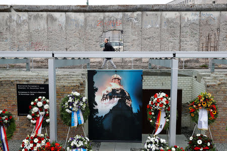 A man walks beside remains of the Berlin Wall at the Topography of Terror museum located at the site of the former Nazi Gestapo and SS headquarters, as Germany marks the 80th anniversary of Kristallnacht, also known as Night of Broken Glass, in Berlin, Germany, November 9, 2018. REUTERS/Fabrizio Bensch