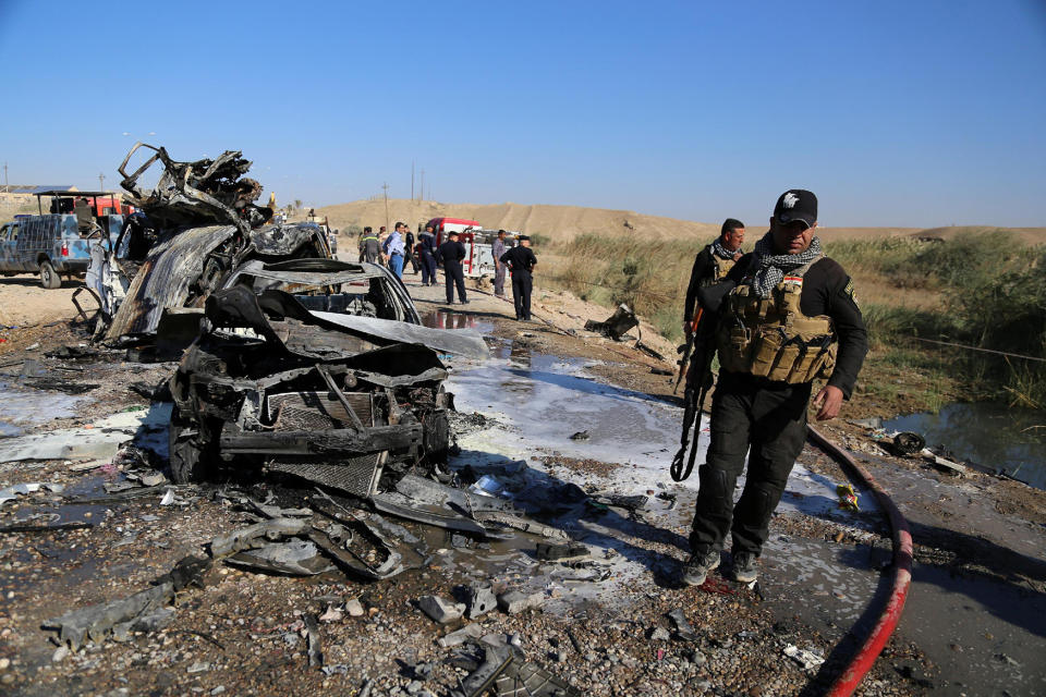 Iraqi security forces inspect the site of bomb attack in Tikrit