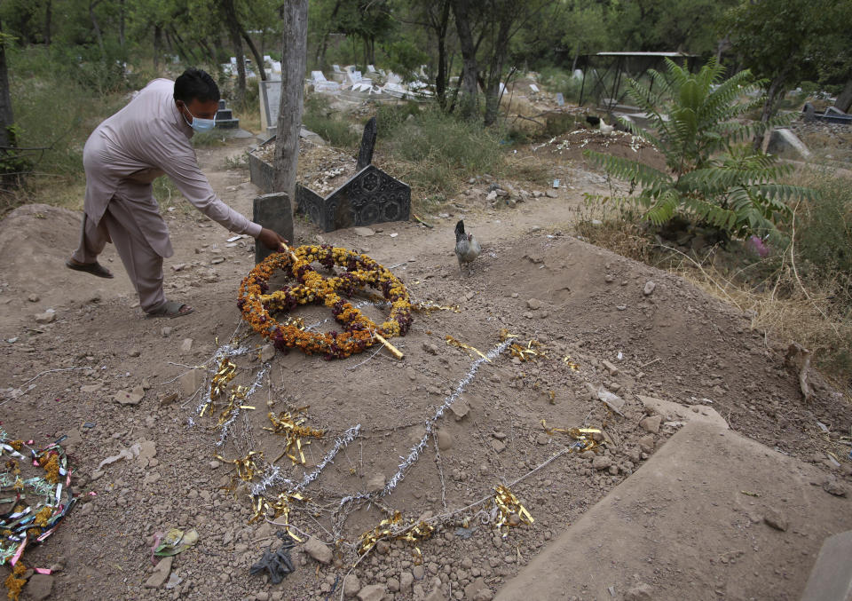 Yasir Lal, a Christian lays a wreath on the grave of his Nadeem Jordon who was killed by gunmen because he rented in a Muslim neighborhood, at a cemetery in Peshawar, Pakistan, Thursday, July 9, 2020. Analysts and activists say minorities in Pakistan are increasingly vulnerable to Islamic extremists as Prime Minister Imran Khan vacillates between trying to forge a pluralistic nation and his conservative Islamic beliefs. (AP Photo/Muhammad Sajjad)