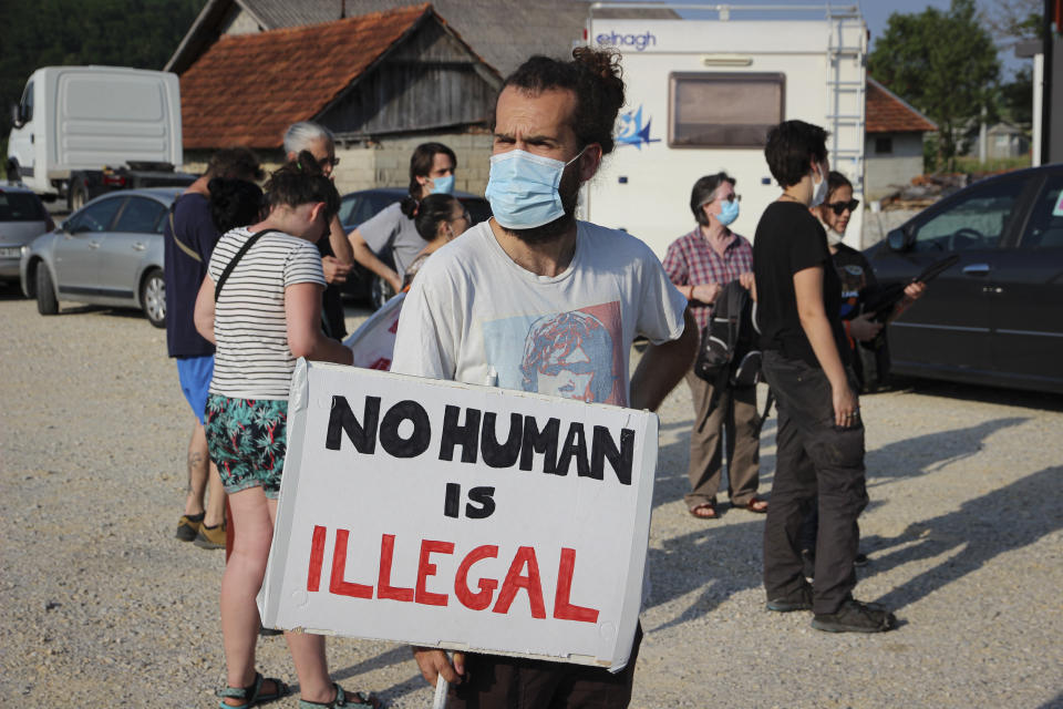 A man holds a banner during a protest against the violent pushbacks of migrants, allegedly conducted by Croatian police, near the border crossing between Croatia and Bosnia Herzegovina in Maljevac, Croatia, Saturday, June 19, 2021. More than one hundred members of human rights NGO's, mostly from Italy, but also from Germany, Austria, Spain and Slovenia blocked the border traffic for about two hours protesting demanding a stop of all deportation of migrants, and cancellation of EU's Frontex operations at borders, preventing migrants from traveling. (AP Photo/Edo Zulic)