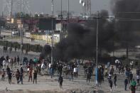 Smoke rises from burning tires as the demonstrators clash with Iraqi security forces during ongoing anti-government protests in Basra