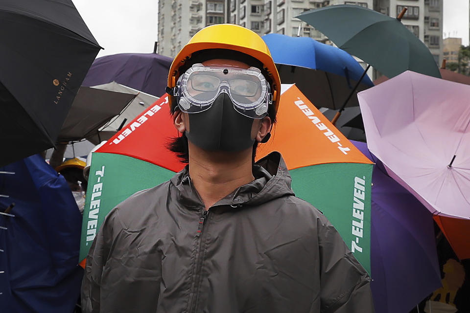 A protester with protection gear stands watch as they use umbrellas and steel barricades to block a road during a march through Sha Tin District in Hong Kong, Sunday, July 14, 2019. Opponents of a proposed Hong Kong extradition law have begun a protest march, adding to an outpouring of complaints the territory's pro-Beijing government is eroding its freedoms and autonomy. (AP Photo/Kin Cheung)