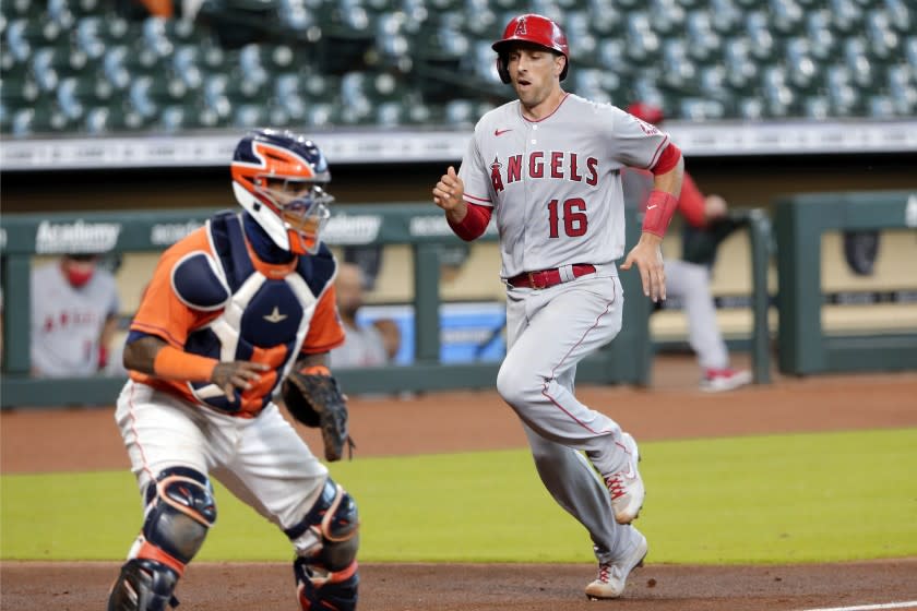 Los Angeles Angels' Jason Castro (16) scores as Houston Astros catcher Martin Maldonado, left, waits.