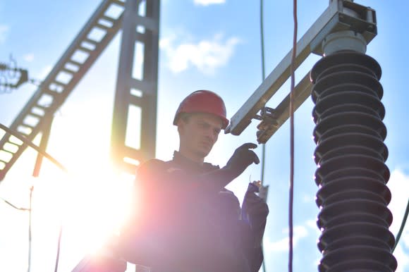 A man in a hard hat standing in front of electrical transmission equipment