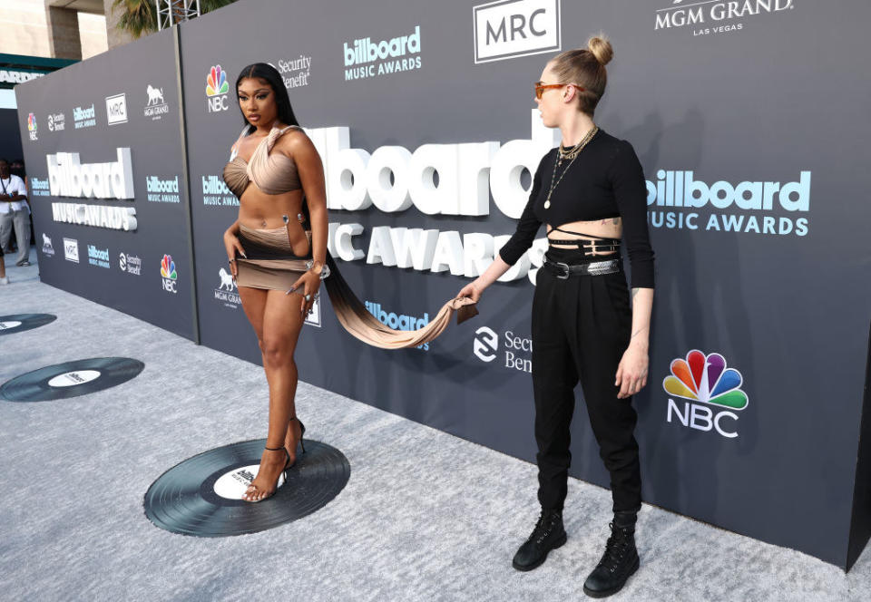 Cara awkwardly holding the end of Megan's dress while pictures are taken