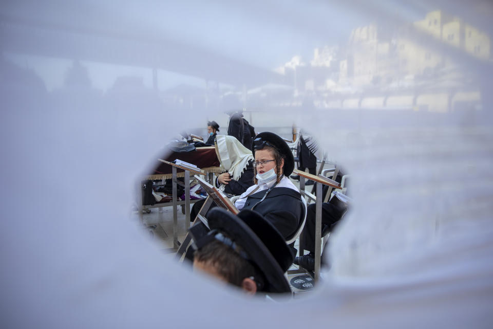 Ultra-Orthodox Jewish men pray in divided sections which allow a maximum of twenty worshipers in line with government measures to help stop the spread of the coronavirus, at the Western Wall, the holiest site where Jews can pray, in Jerusalem's Old City, Thursday, July 16, 2020. (AP Photo/Oded Balilty)