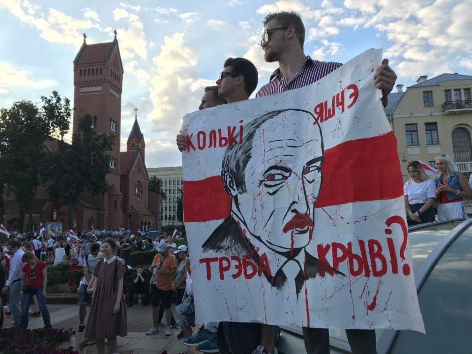 "How much more blood will it take?" is written on the poster with the face of Belarusian dictator Aleksandr Lukashenko held by a young man in Independence Square during an opposition protest in Minsk in August 2020. (Ulf Mauder/picture alliance via Getty Images)