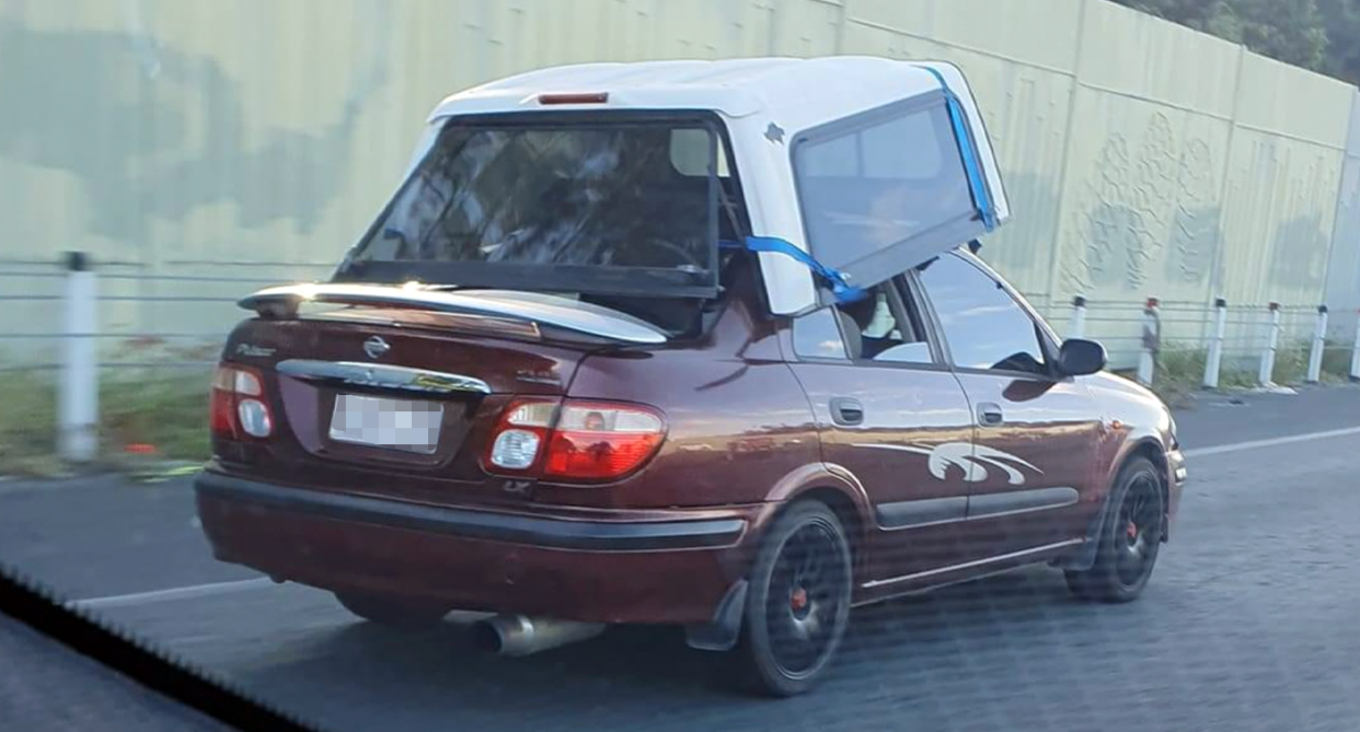 The canopy or cabin or a utility can be seen strapped to the roof of a Nissan sedan in Queensland. 