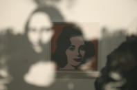 In this photo taken Wednesday, May 15, 2019, in a display of female icons, Elizabeth Taylor is reflected in an image of the Mona Lisa at the exhibition, "Andy Warhol _ From A to B and Back Again" in San Francisco. A retrospective of Andy Warhol's work on display at the San Francisco Museum of Modern Art captures his use of artwork to give his subjects personas the way people do now using social media. (AP Photo/Eric Risberg)