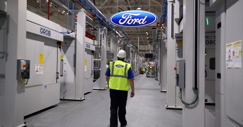 An employee walks past a Ford logo in the yet-to-be-completed engine production line at a Ford factory