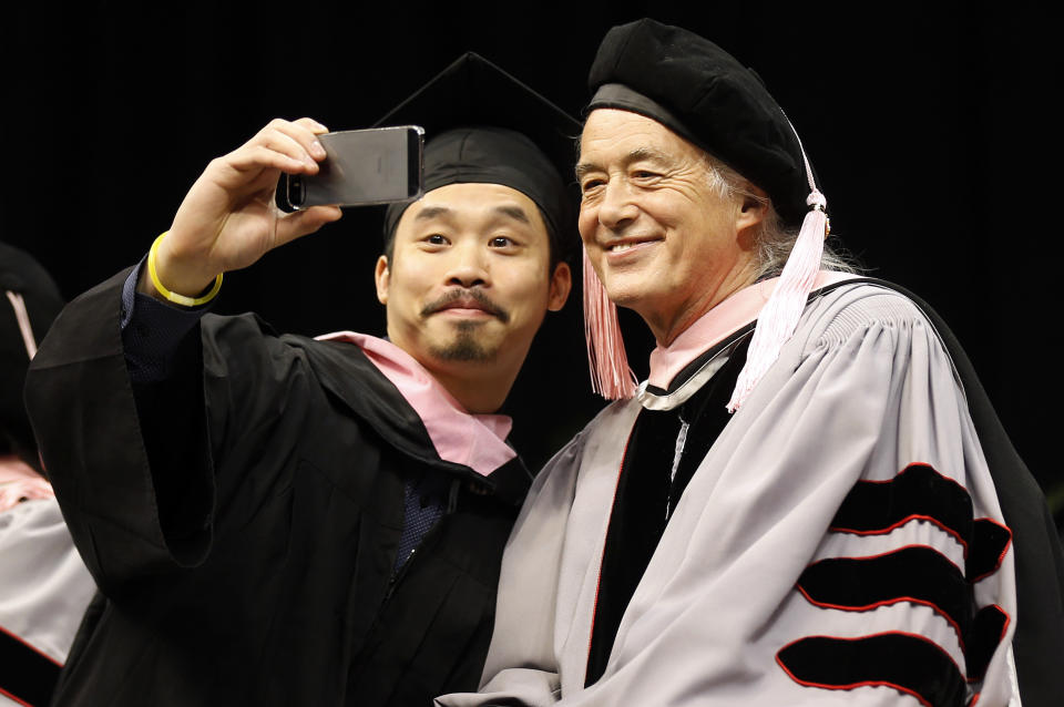 Just before receiving his degree, Berklee College of Music graduate Wing-Ching Poon of Edmonton, Canada takes a "selfie" with former Led Zeppelin guitarist Jimmy Page, who received an Honorary Degree of Doctor of Music from the school during their commencement in Boston, Saturday, May 10. 2014. (AP Photo/Winslow Townson)