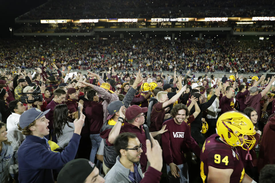 Arizona State fans rush the field after the team's NCAA college football game against Oregon, Saturday, Nov. 23, 2019, in Tempe, Ariz. Arizona State won 31-28. (AP Photo/Matt York)