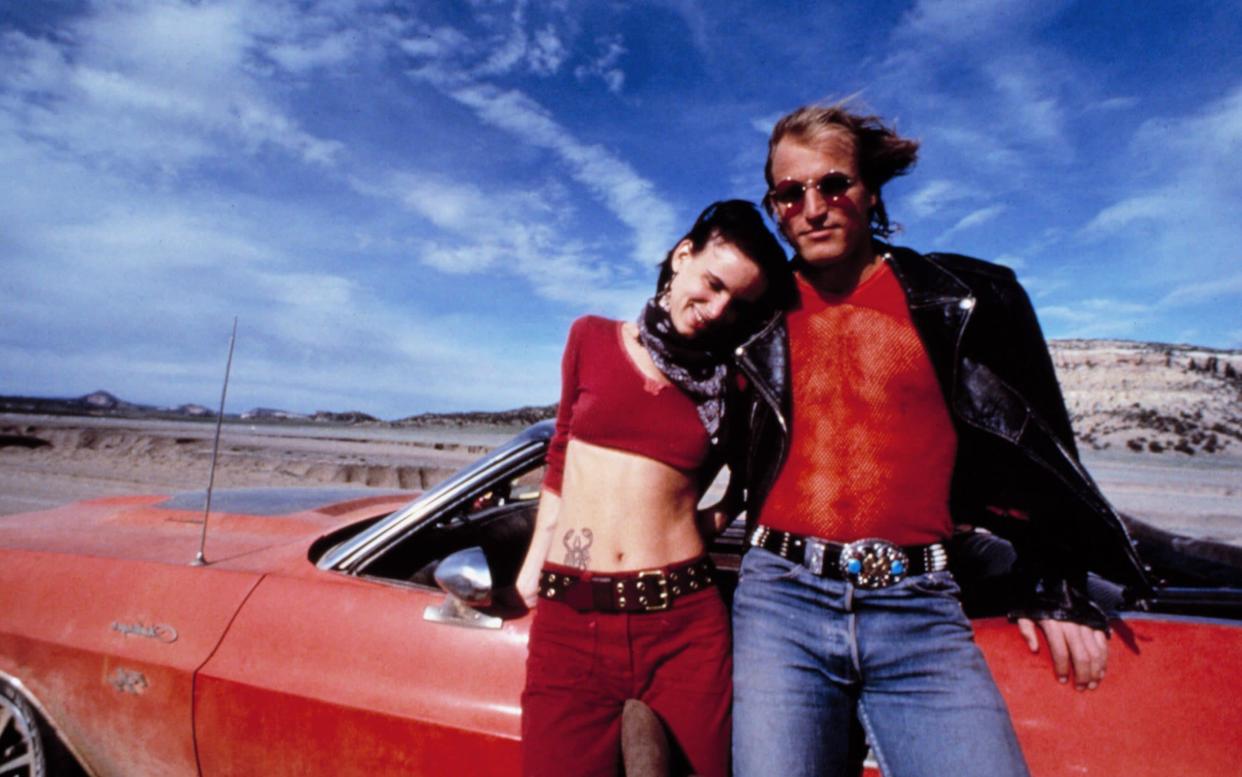 Juliette Lewis and Woody Harrelson by a red car