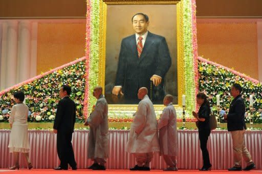 Buddhist monks and Unification Church devotees walk past a portrait of the late Sun Myung Moon at his wake in Gapyeong. Thousands of tearful mourners descended Thursday on the South Korean headquarters of the church to offer prayers to their late "messiah"