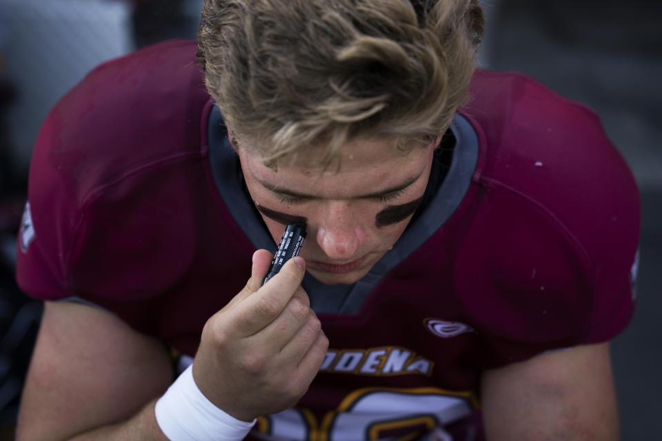 El Modena center Jack Stein applies black stripes before the team's high school football game with El Dorado in Orange, Calif., Friday, March 19, 2021. (AP Photo/Jae C. Hong)