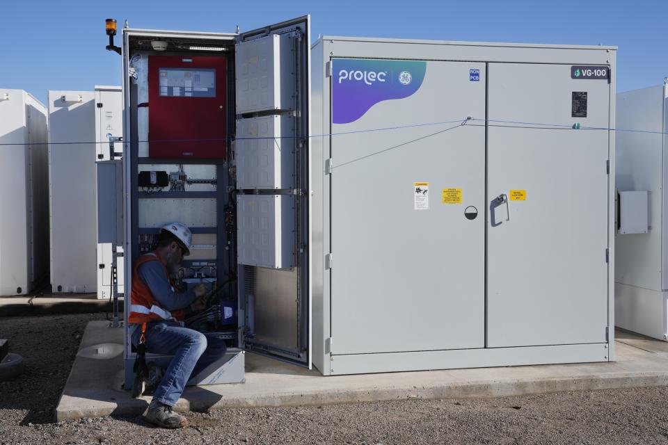 A worker does checks on battery storage infrastructure at Orsted's Eleven Mile Solar Center lithium-ion battery storage energy facility Thursday, Feb. 29, 2024, in Coolidge, Ariz. Batteries allow renewables to replace fossil fuels like oil, gas and coal, while keeping a steady flow of power when sources like wind and solar are not producing. (AP Photo/Ross D. Franklin)