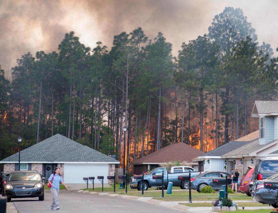 Residents evacuate their homes as a wildfire burns in the woods behind the houses on Weatherstone Circle in Pensacola on Monday, May 7, 2018. A recent study led by a Milton researcher indicates wildfires are becoming larger and more frequent.