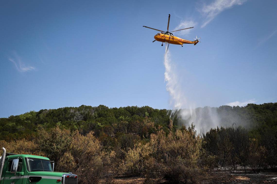 A Type 1 Helicopter drops lake water on a blaze along FM 1148 Tuesday, July 19, 2022, near Possum Kingdom Lake in Graham. The fire has consumed 500 acres.