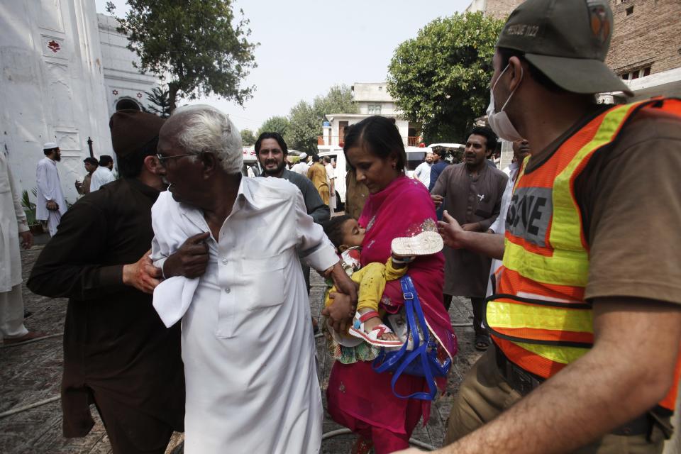 ATTENTION EDITORS - VISUAL COVERAGE OF SCENES OF INJURY OR DEATH Rescue workers escort a woman carrying a dead child from the site of a blast at a church in Peshawar September 22, 2013. A pair of suicide bombers blew themselves up outside the church in the Pakistani city of Peshawar, killing 40 people after Sunday mass, security officials said.REUTERS/Fayaz Aziz (PAKISTAN - Tags: RELIGION CIVIL UNREST) TEMPLATE OUT