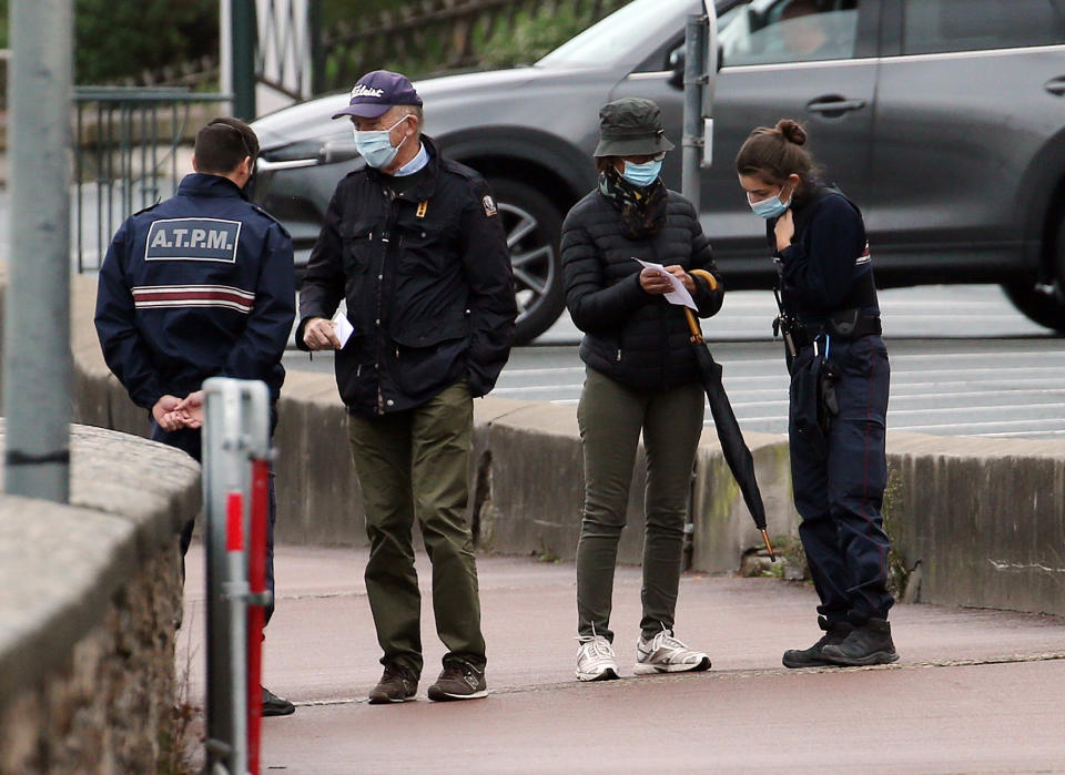 Police officers check documents to ensure that confinement measures due to the coronavirus are upheld in Saint Jean de Luz, southwestern France, Tuesday, Nov.3, 2020. French supermarkets are banned from selling flowers and books but they can still sell baby care products, according to a decree published Tuesday laying out new rules for what are considered "essential" items during a monthlong lockdown effort to slow virus infections and save lives. (AP Photo/Bob Edme)