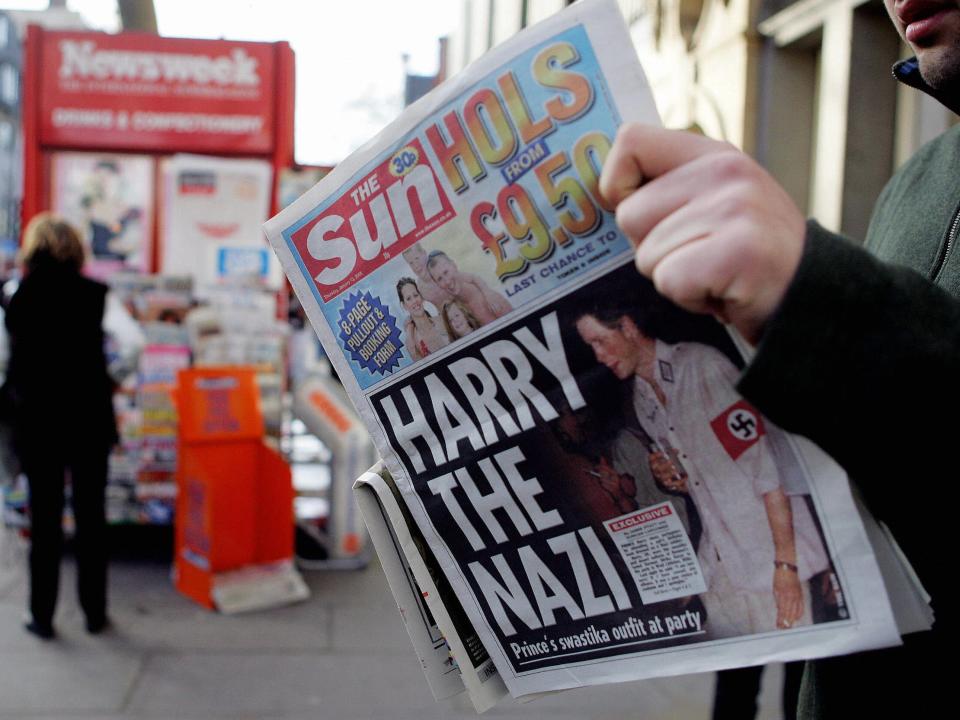 A man reads The Sun newspaper in London 13 January, 2005, with a headline about Prince Harry wearing a Nazi uniform at a costume party.