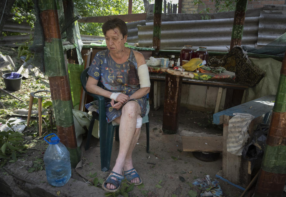 A woman injured when her house was damaged by the Russian shelling sits shocked in the yard of her house in Bakhmut, Donetsk region, Ukraine, Sunday, June 26, 2022.(AP Photo/Efrem Lukatsky)