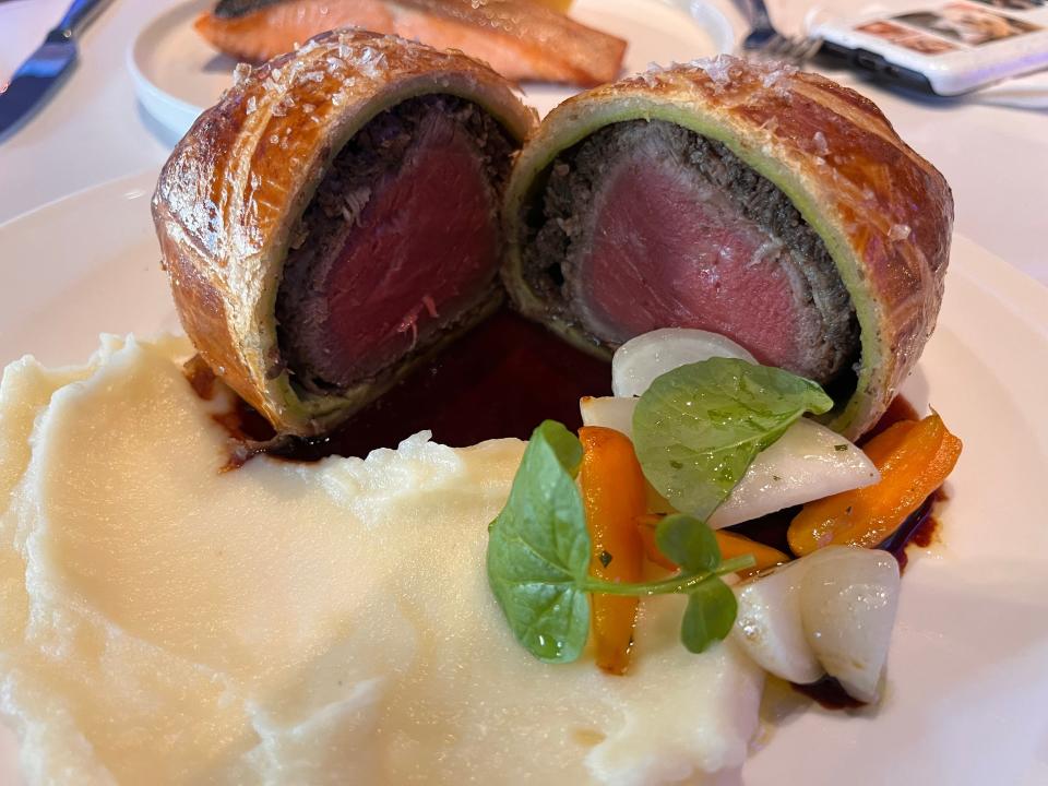 Beef Wellington with pink medium-rare meet, vegetables, and potato purée
