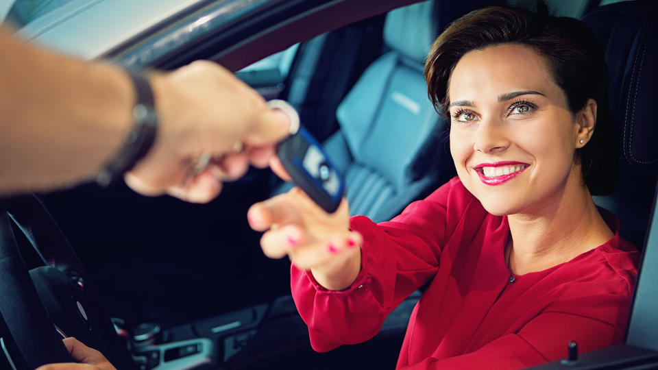 Car dealer is giving car key to a businesswoman.