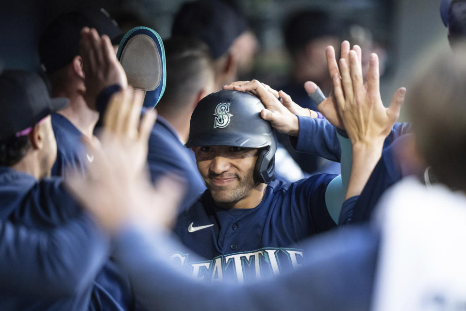 Seattle Mariners' Jose Caballero is congratulated by teammates in the dugout after scoring a run during the fifth inning of a baseball game against the Minnesota Twins, Monday, July 17, 2023, in Seattle. (AP Photo/Stephen Brashear)