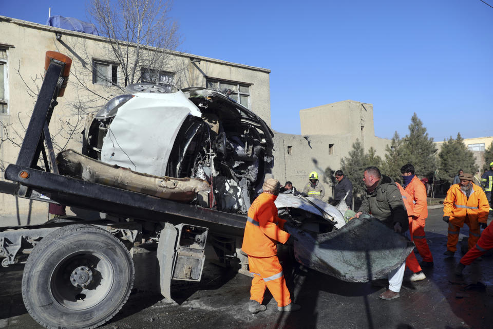 Afghan security personnel and municipality workers remove a damaged vehicle after a roadside bomb in Kabul, Afghanistan, Tuesday, Dec. 22, 2020. A roadside bomb tore through a vehicle in the Afghan capital of Kabul Tuesday, killing multiple people, police said. (AP Photo/Rahmat Gul)