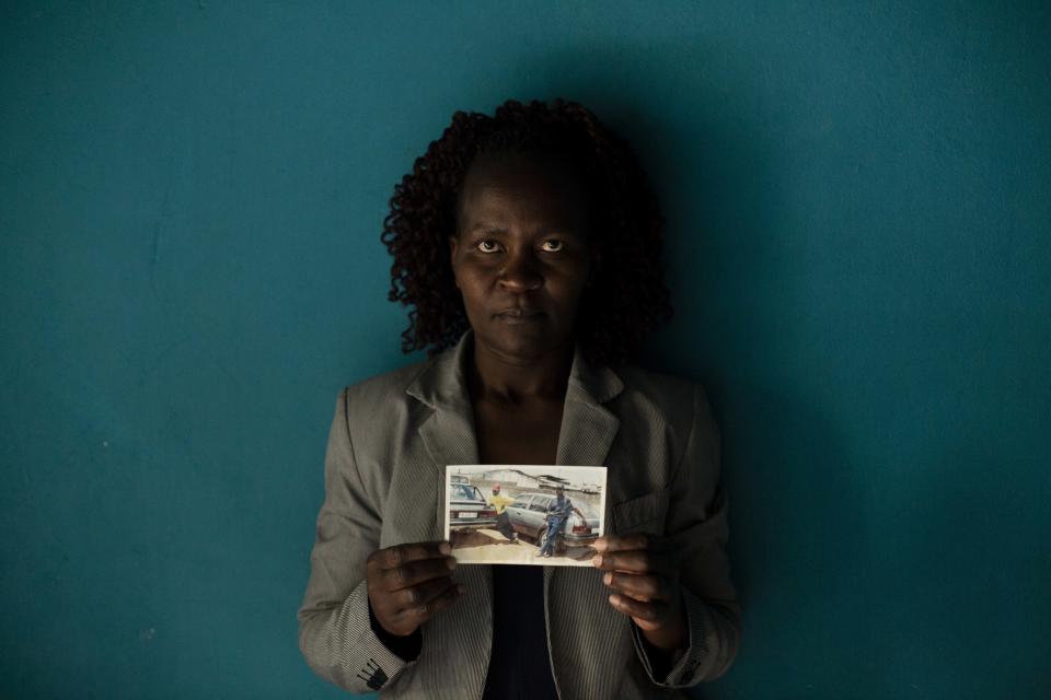 In this Friday, Aug. 24, 2018 photo, Zimbabwean migrant Banele Nkomo holds a photograph of her missing brother, Francis. She doesn't know what happened to him and hasn't heard from him for years. She says she misses him every day and wants to know whether he passed away and where his body is in order to find closure. (AP Photo/Bram Janssen)