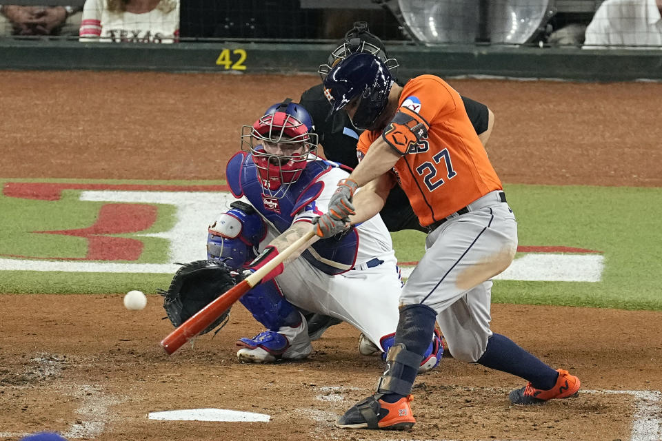 Houston Astros' Jose Altuve (27) hits a single as Texas Rangers catcher Jonah Heim reaches for the pitch during the second inning in Game 4 of the baseball American League Championship Series Thursday, Oct. 19, 2023, in Arlington, Texas. (AP Photo/Tony Gutierrez)