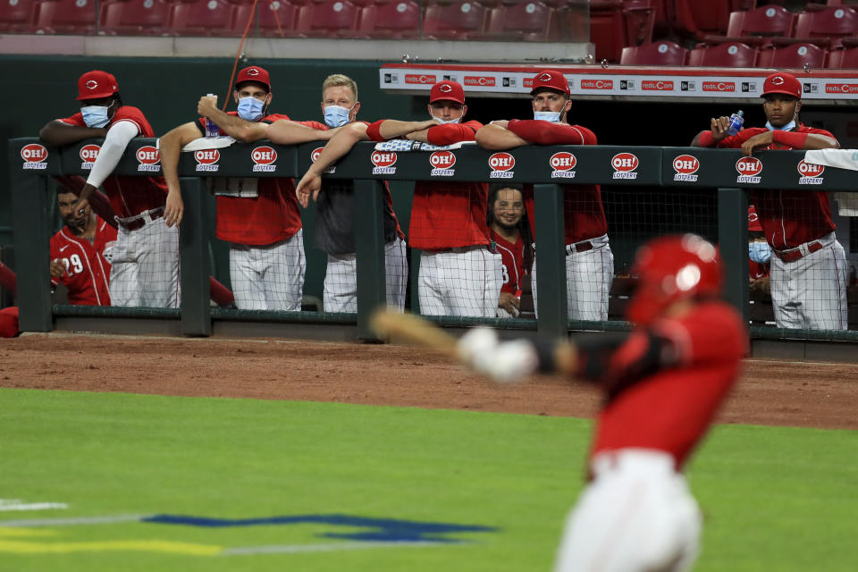 Members of the Cincinnati Reds wear masks as they watch the game from the dugout during an exhibition baseball game against the Detroit Tigers at Great American Ballpark in Cincinnati, Tuesday, July 21, 2020. The Reds won 9-7. (AP Photo/Aaron Doster)