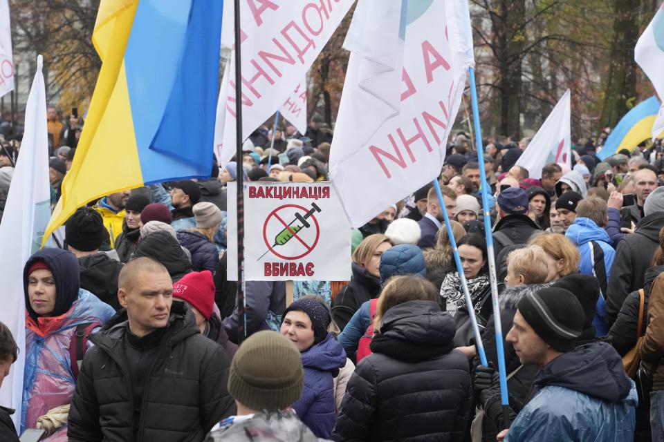 Demonstrators, one carrying a poster reading "Vaccination kills" gather to protest against COVID-19 restrictions and vaccine mandates in Kyiv, Ukraine, Wednesday, Nov. 3, 2021. In a bid to stem contagion, Ukrainian authorities have required teachers, government employees and other workers to get fully vaccinated by Nov. 8 or face having their salary payments suspended. In addition, proof of vaccination or a negative test is now required to board planes, trains and long-distance buses. (AP Photo/Efrem Lukatsky)